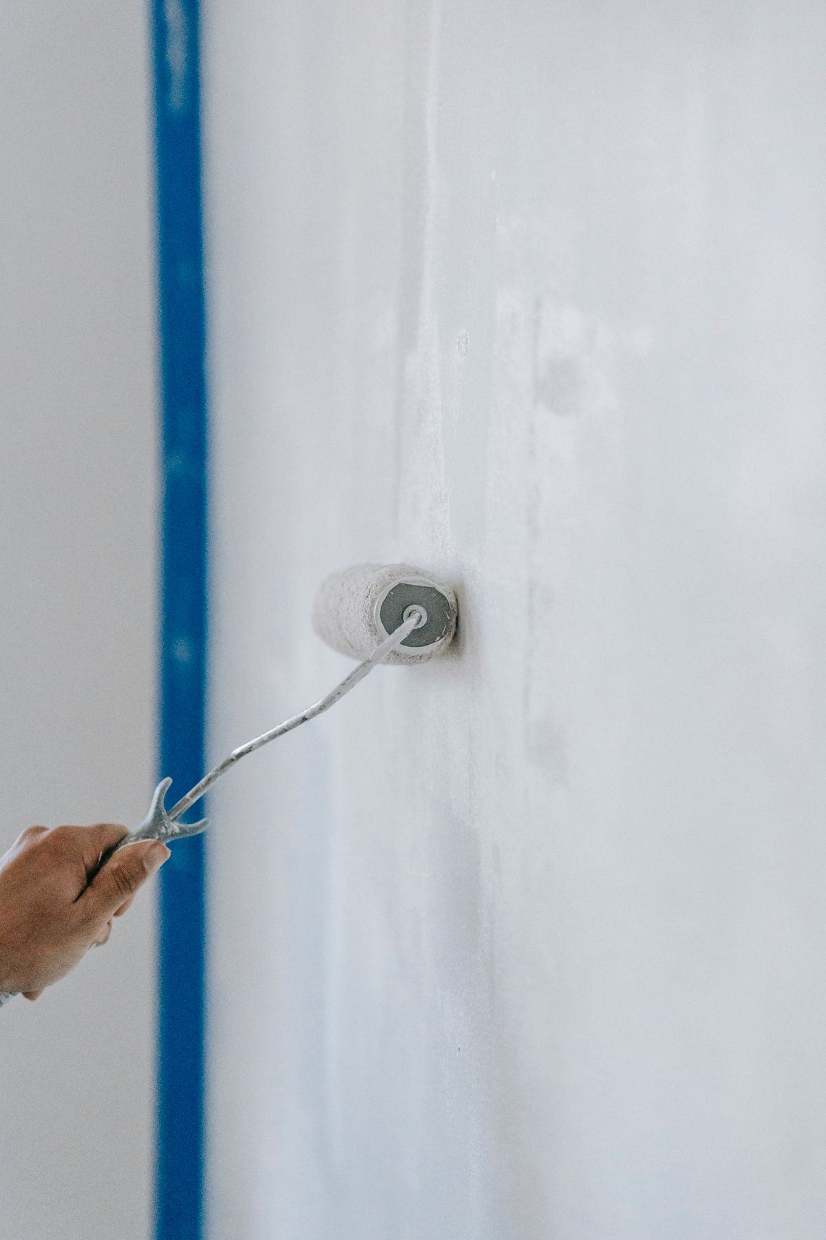 Person applying white paint to a wall with a roller
